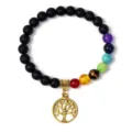 Chakra stone bracelet detail view featuring matte black beads and golden tree of life charm. - 1