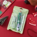 Close-up of Christmas stationery set featuring multi-color pen and erasers in green pouch. - Christmas Set 6-Piece / Green