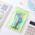Cute cartoon stationery set detail showing colorful pens and dinosaur eraser in a green bag. - Dinosaur Set 6-Piece / Green