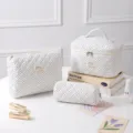 Set of three white quilted cotton polka dot cosmetic bags displayed with beauty props - Black White Polka Dot