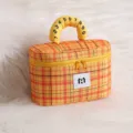 Detail of yellow plaid cosmetic bag with numbered handle and soft fur background - Citrus