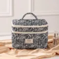 Detailansicht einer eleganten, gesteppten Kosmetiktasche mit Blumenmuster auf Goldseide - 23*16*16cm / Schwarze Rose Anhänger