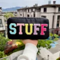 Black nylon cosmetic bag with colorful STUFF embroidery and gold glitter trim. - Black
