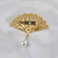 Detail view of the safety pin closure on the back of the golden fan-shaped brooch. - Pin Style