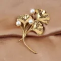 Close-up view of golden stainless steel ginkgo leaf brooch with pearls on silk. - Style 02 Triple Leaf / Gold