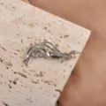 Macro detail of an artistic silver wave brooch featuring sparkling clear rhinestones on stone - White Gold