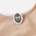 Primer plano detallado de broche magnético con lazo dorado y borde de perlas - Lazo Negro