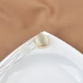 Eleganter goldener Manschettenknopf mit Katzenaugenstein auf weißer Keramik - Weißer Katzenaugenstein