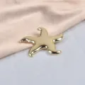 Close-up detail of a glossy golden starfish brooch on elegant pink silk fabric - Starfish / Gold