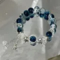 Blue cracked glass bead bracelet detail with star charms and reflective background setup. - Galaxy Star Bracelet (S6234) / Blue