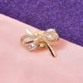 Detailopname van een elegante gouden strikbrosche met fonkelende zirkonia-kristallen - Goud