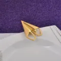 Dettaglio di una spilla per abiti a forma di aeroplanino di carta in acciaio dorato - Oro
