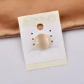 Detaillierte Makroansicht einer minimalistischen cremefarbenen runden Magnetbrosche - Runder Stil / Katzenauge