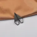 Primo piano di una spilla minimalista a forma di aereo di carta in acciaio nero. - Nero