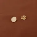Detailed close-up of a minimalist round gold metal brooch pin with secure butterfly clutch - Round / Gold