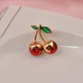 Détail d'une broche cerise en cristal avec tige dorée sur une assiette décorative - Cerise