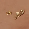 Detailaufnahme einer eleganten goldfarbenen Herz-Sicherheitsnadel auf Satin-Stoff - Herz Nadel Schnalle