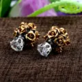 Makroaufnahme von doppelseitigen Ohrringen mit goldenen Rosen und klarem Zirkon. - Zirkonia Stecker Stil / Goldene Rose Blume