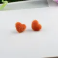 Detailansicht der orangefarbenen flauschigen Herzohrringe aus Nerzfell für Wintermode - Orange
