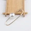 Detail einer goldfarbenen Sicherheitsnadel-Brosche mit großer weißer Perle - Stil mit großer Perle / Gold