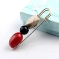 Detailansicht einer goldenen Sicherheitsnadel-Brosche mit roten, schwarzen und marmorierten Perlen. - Modell 02 (Rote Perle + Schwarz + Creme Marmor)