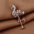 Elegant rose gold flamingo brooch with sparkling crystal details on brown satin fabric - Copper