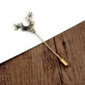 Detalle de un alfiler de solapa vintage con cabeza de ciervo sobre madera y blanco. - Cabeza de Alce Bronce