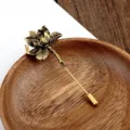 Detail van een vintage lotus sierspeld op een rustieke houten schotel accessoire - Lotus Antiek Brons