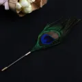 Detailed view of the natural peacock feather brooch with a golden long pin. - Peacock Blue