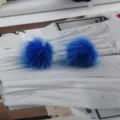 Makro-Detail von leuchtend blauen Pompon-Ohrsteckern aus echtem Nerzfell auf weiß - Blau