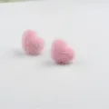 Nahaufnahme der rosafarbenen, flauschigen Herzohrringe aus Nerzfell für den Winter - Rosa