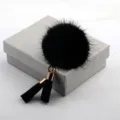 Eleganter schwarzer Nerzfell-Bommel-Anstecknadel mit modischen Quasten auf einer Box. - Schwarz