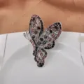 Detailansicht einer Vintage-Schmetterlingsbrosche mit lila Strass auf weißem Teller - Stil 02 Purpurrot