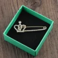 Detailansicht einer eleganten goldenen Kronen-Sicherheitsnadel-Brosche mit Strasssteinen - Kronen-Stil / Krone