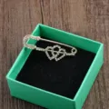 Eleganter goldfarbener Sicherheitsnadel-Brosche mit Strass-Herzen in einer blaugrünen Box - Doppelherz Stil / Doppelherz
