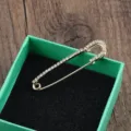 Detailansicht einer goldenen Sicherheitsnadel-Brosche mit funkelnden Strasssteinen - Einreihiger Diamant-Stil / Einreihig