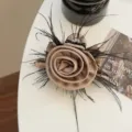 Detailed macro view of an elegant fabric rose and black feather hair claw clip - Hair Claw / Khaki