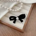 Elegant black velvet bow hair clip with central white pearl accent on jewelry display - Black-Large (240104)