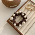 Elegante elastico marrone con grandi perle bianche su vassoio gioielli. - Marrone