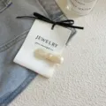 Niedliche bogenförmige Haarklammer aus Acetat in Geleefarbe auf Denim-Hintergrund - Schleifen-Stil / Milchweiß