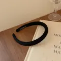 Elegant black knitted thin headband for women featuring a handmade label on a warm wooden desk - Black