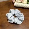Weicher hellblauer Polka Dot Stoff Scrunchie Haargummi auf Holzgrund - Stoffhaargummi mit Punktmuster / Cremeblau