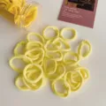 Set of vibrant yellow elastic hair ties in a clear plastic jar on a white surface - 50 Pcs Bag / Yellow