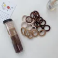Detail shot of elastic hair ties in neutral earth tones with a clear storage tube. - 20 Piece Set / Milk Coffee Series