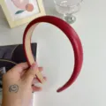Detail view of a red padded headband with smooth texture and elegant high-top design. - Red PU Leather Hair Band (210816)
