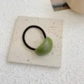 Elegant minimalist green acrylic jelly hair tie with black elastic band on stone - Green