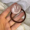 Pink acrylic marble-patterned hair tie featuring a smiley face design and brown elastic. - Smiley Face Acrylic Style / Pink