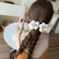 Detailansicht der weißen gestrickten Wollblumen-Haarspangen an einem geflochtenen Zopf. - Gebrochenes Weiß