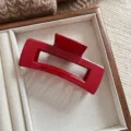 Detalle de una pinza de pelo rectangular roja grande colocada en una bandeja de madera - Rectangular rojo