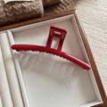 Detailaufnahme einer glänzenden roten übergroßen Haarklammer in einer edlen Holzbox - Rot Gerade